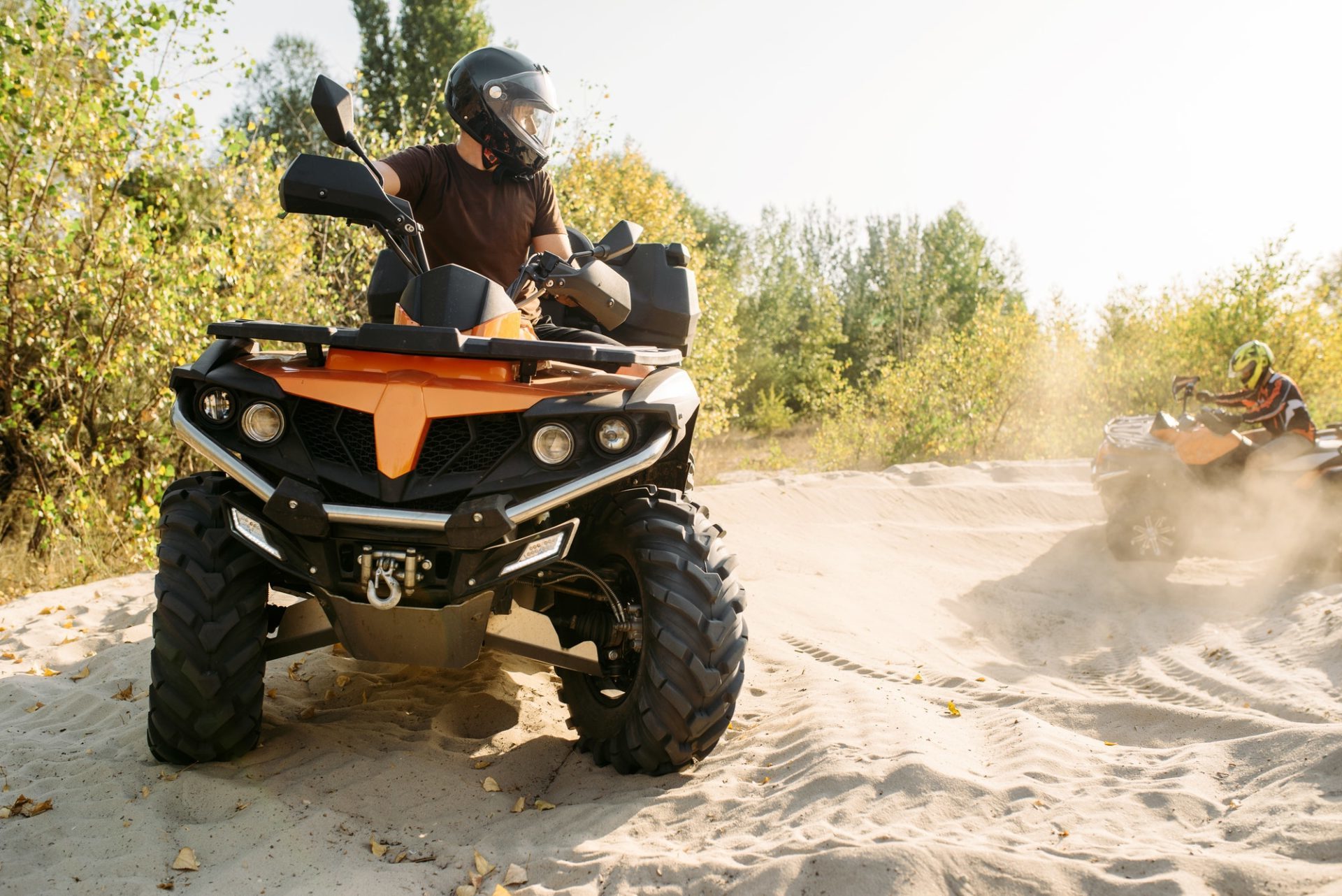 two-atv-riders-in-helmets-ride-in-a-circle-on-sand-e1645568779414.jpg